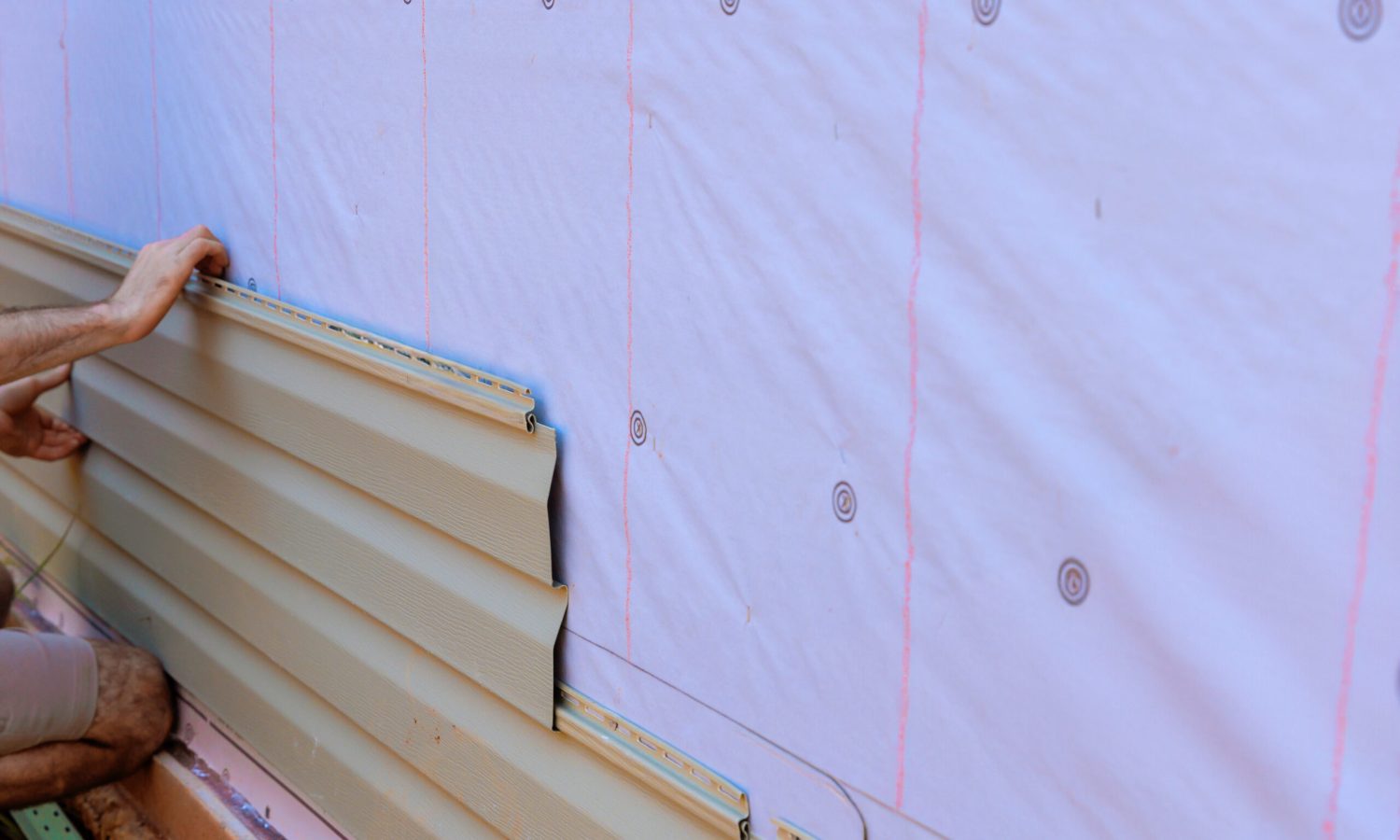 In process of installing vinyl siding on new home facade, handyman installs vinyl PVC siding